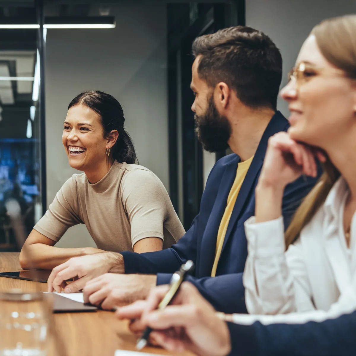 Happy businesswoman laughing while leading a meeting with her colleagues. Group of diverse businesspeople working together in a modern workplace. Business colleagues collaborating on a project.